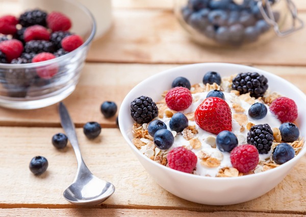 Avižų dubenėlis su uogomis ir sėklomis ant medinio stalo